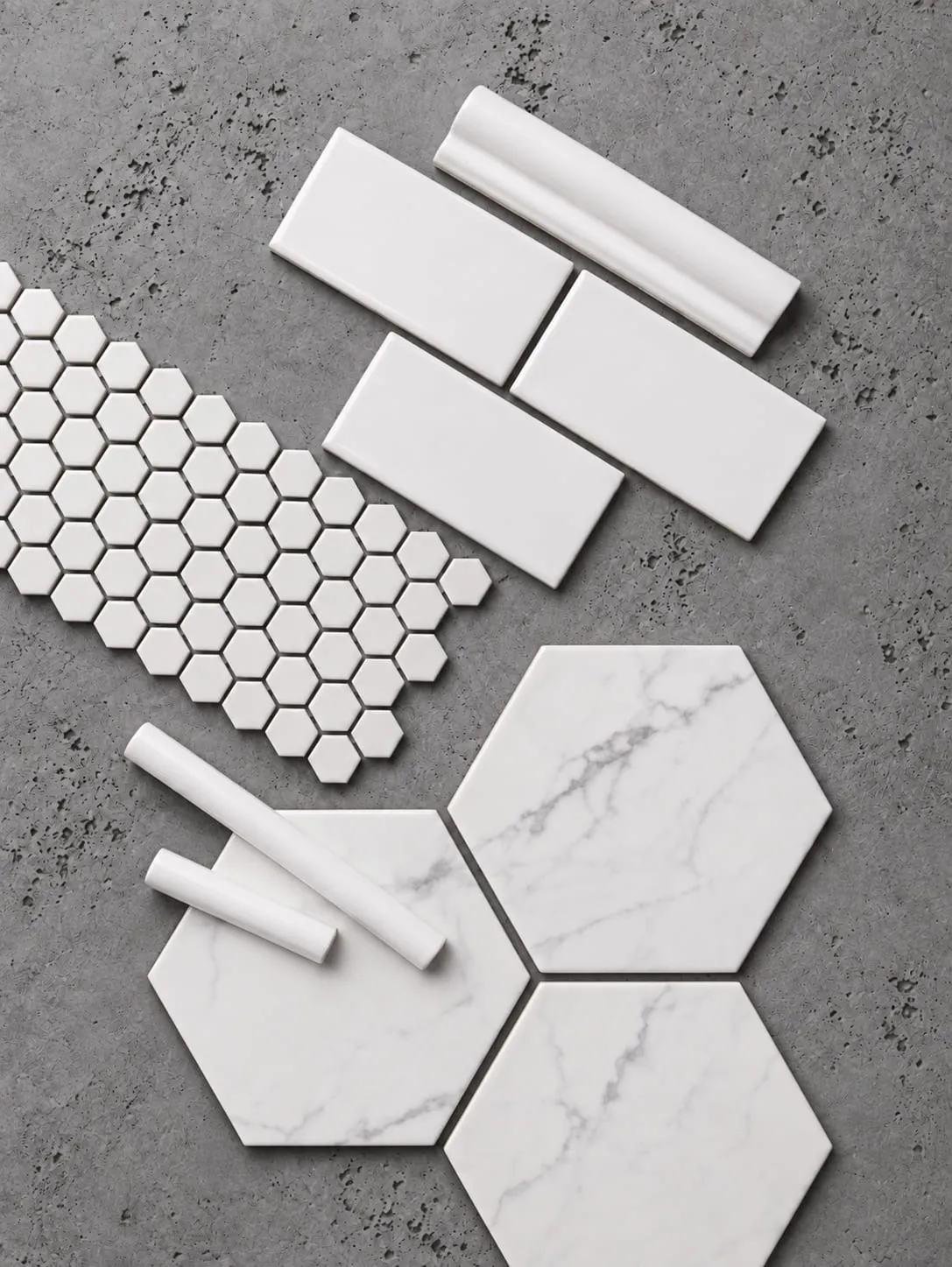 Tile samples laid out on concrete: white hexagon mosaic, subway tile, marble hexagons, and trim pieces